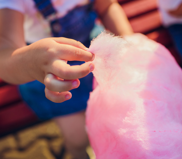 girl picking off a piece of pink cotton candy