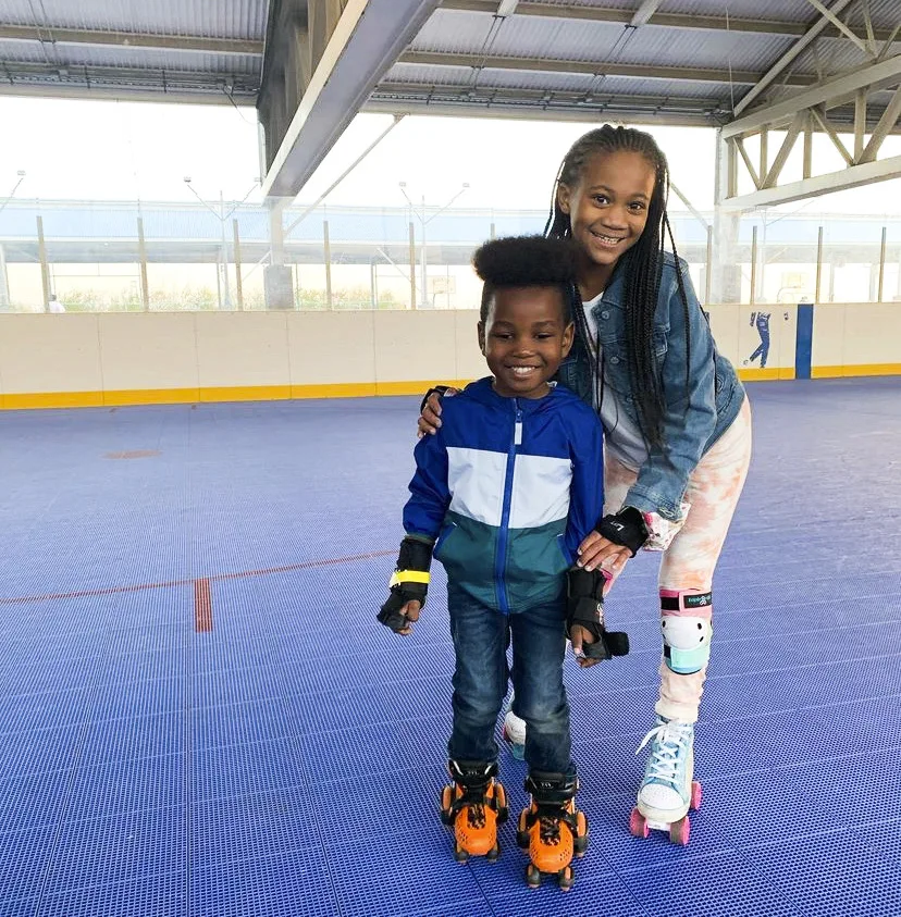 sister with her arms over her young brother smiling