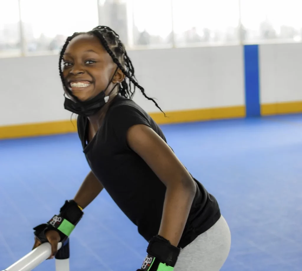 young girl smiling while using a skate mate for balance