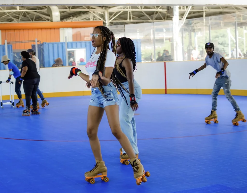 two teenage girls skating while other people skate in the background